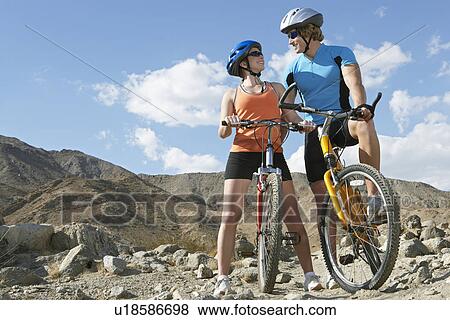 Stock Photo - Young couple on bicycles in mountains. Fotosearch