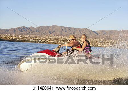 Young couple riding jetski on lake View Large Photo Image Stock Image - Young couple riding jetski on lake. Fotosearch
