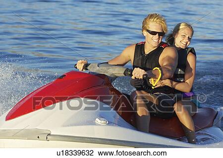 Stock Image - Young couple riding jetski on lake. Fotosearch