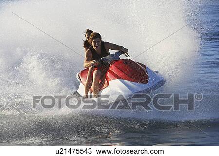 Stock Image - Young couple riding jetski on lake. Fotosearch