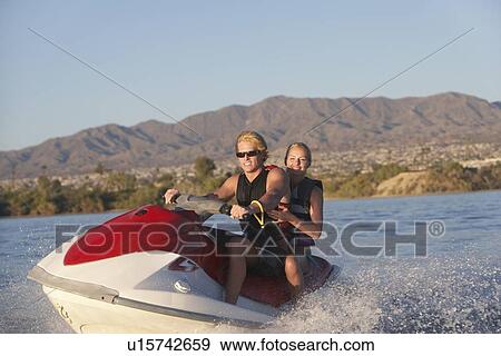 Stock Photo - Young couple riding jetski on lake. Fotosearch
