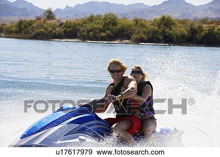 Stock Photo - Young couple riding jetski on lake, portrait. Fotosearch