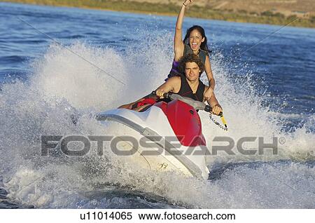 Stock Photography - Young couple riding jetski on lake. Fotosearch