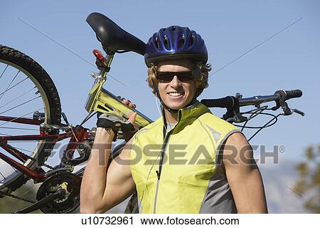 Young man carrying bicycle, outdoors, portrait View Large Photo Image Stock Image - Young man carrying bicycle, outdoors, portrait. Fotosearch