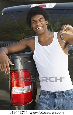 Young man holding car key standing by pick up truck, portrait View Large Photo Image Stock Image - Young man holding car key standing by pick up truck, portrait. Fotosearch