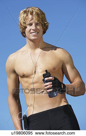 Stock Photography - Young man holding water bottle, outdoors, portrait. Fotosearch