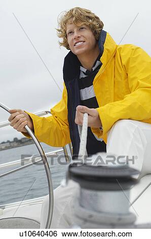 Young man standing at yacht helm View Large Photo Image Stock Photograph - Young man standing at yacht helm. Fotosearch