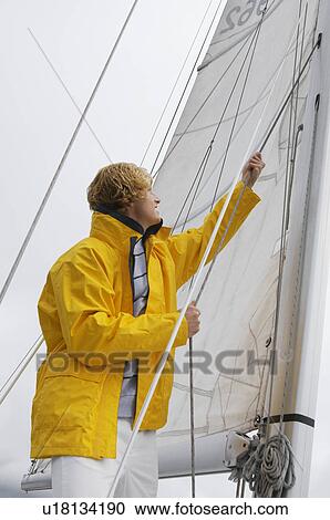 Young man standing on yacht in sea View Large Photo Image Stock Image - Young man standing on yacht in sea. Fotosearch