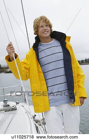 Stock Photo - Young man standing on yacht in sea. Fotosearch