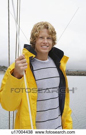Stock Photo - Young man standing on yacht, portrait. Fotosearch