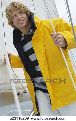 Stock Photo - Young man standing on yacht. Fotosearch