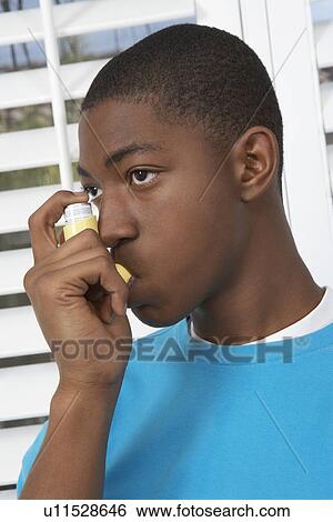 Stock Photograph - Young man using asthma inhaler. Fotosearch