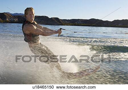 Stock Image - Young man wakeboarding on lake. Fotosearch
