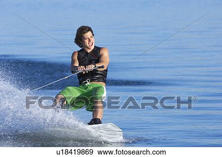 Stock Photo - Young man wakeboarding on lake. Fotosearch