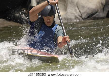 Stock Image - Young man whitewater kayaking. Fotosearch