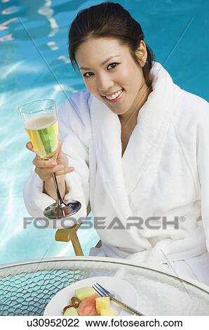 Young woman drinking champagne by swimming pool, portrait View Large Photo Image Stock Image - Young woman drinking champagne by swimming pool, portrait. Fotosearch