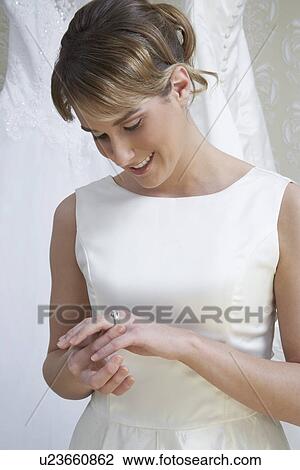 Stock Image - Young woman examining ring on finger. Fotosearch