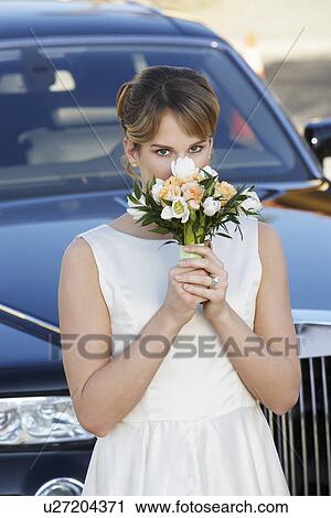 Young woman holding bouquet in front of limousine, portrait View Large Photo Image Stock Image - Young woman holding bouquet in front of limousine, portrait. Fotosearch