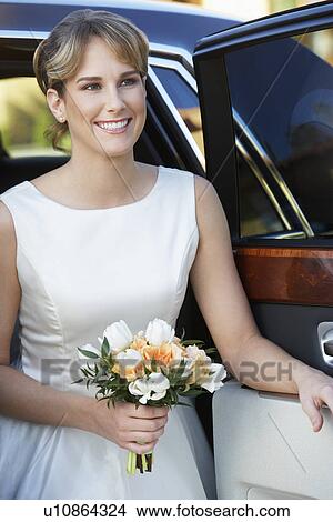 Picture - Young woman holding bouquet in open door of limousine, portrait. Fotosearch