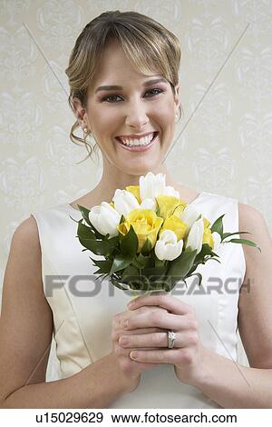 Stock Photo - Young woman holding bouquet, portrait. Fotosearch
