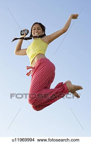 Picture - Young woman jumping with mp3 player in hand. Fotosearch