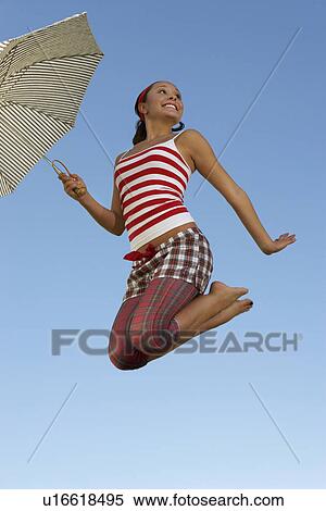 Stock Photography - Young woman mid air with umbrella. Fotosearch