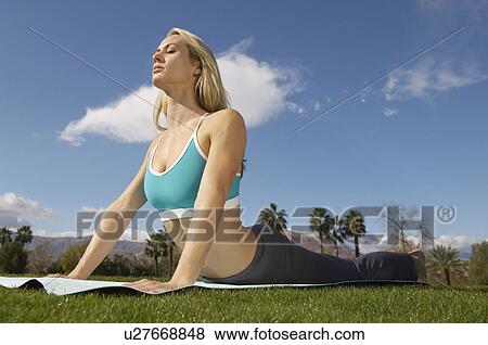 Stock Photo - Young woman performing yoga exercises in park. Fotosearch