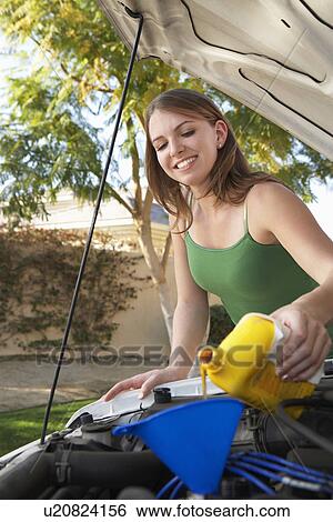 Young woman pouring oil into car engine View Large Photo Image Stock Photograph - Young woman pouring oil into car engine. Fotosearch