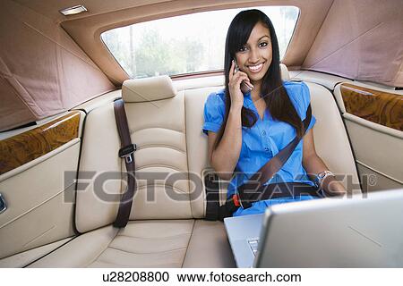 Stock Image - Young Woman Talking on Phone in Car. Fotosearch