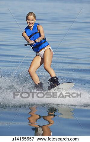 Stock Photo - Young woman wakeboarding on lake. Fotosearch