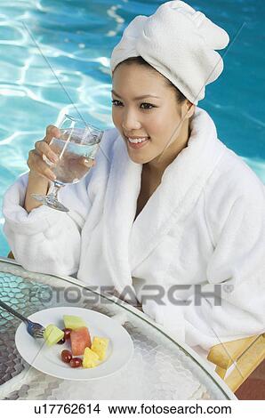 Young woman wearing bathrobe, drinking by swimming pool View Large Photo Image Picture - Young woman wearing bathrobe, drinking by swimming pool. Fotosearch