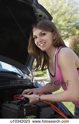 Young woman with jumper cables by car View Large Photo Image Stock Image - Young woman with jumper cables by car. Fotosearch