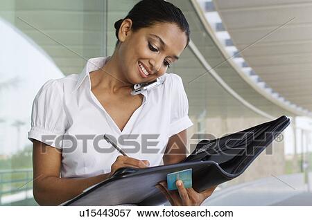 Stock Photo - Young Woman Writing in a Planner. Fotosearch