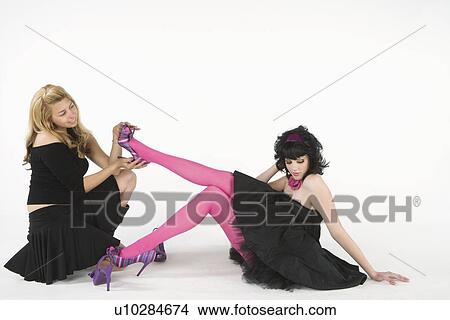 Assistant removes high heeled shoes from woman sitting on floor in party dress View Large Photo Image Picture - Assistant removes high heeled shoes from woman sitting on floor in party dress. Fotosearch