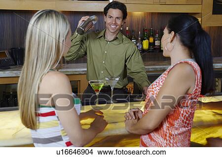 Picture - Bartender Mixing Drinks for Women at Bar. Fotosearch