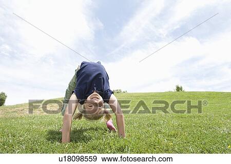 Stock Photo - Bending over backwards, girl on grass. Fotosearch