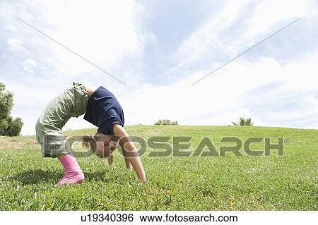 Stock Photograph - Bending over backwards, girl on grass. Fotosearch