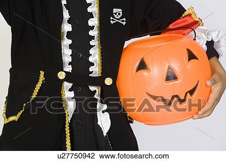 Stock Image - Boy (7-9) wearing Halloween costume, with jack-o-lantern. Fotosearch