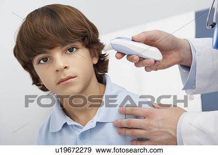 Boy having temperature taken with ear thermometer, portrait View Large Photo Image Stock Photo - Boy having temperature taken with ear thermometer, portrait. Fotosearch