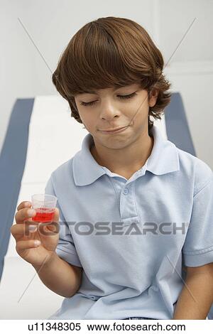 Stock Photography - Boy holding liquid medicine. Fotosearch
