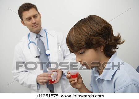 Stock Photography - Boy holding medicine in liquid measure. Fotosearch