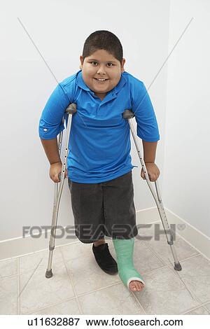 Stock Photo - Boy standing with crutches. Fotosearch