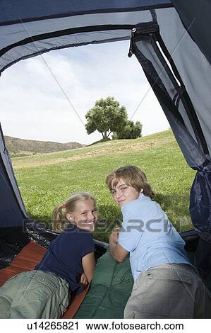 Stock Image - Brother and sister lie in a tent, looking back over their shoulders. Fotosearch