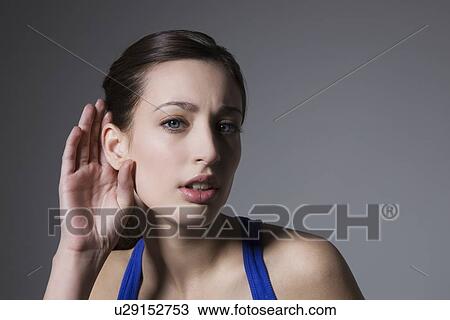 Stock Image - Brunette with hand behind ear. Fotosearch