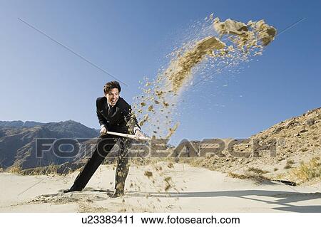 Stock Image - Businessman Digging With Spade in the Desert. Fotosearch