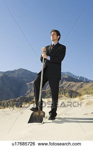Businessman Holding Spade in the Desert View Large Photo Image Stock Photograph - Businessman Holding Spade in the Desert. Fotosearch