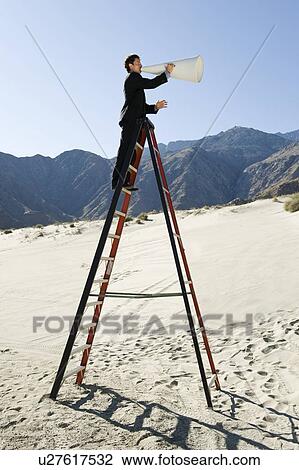 Stock Image - Businessman on Stepladder Using Megaphone in Desert. Fotosearch