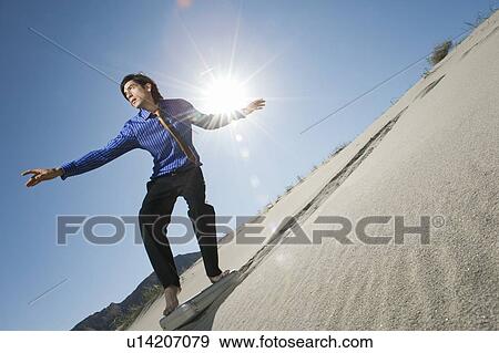 Businessman Surfing Downhill On Briefcase in the Desert View Large Photo Image Stock Photo - Businessman Surfing Downhill On Briefcase in the Desert. Fotosearch