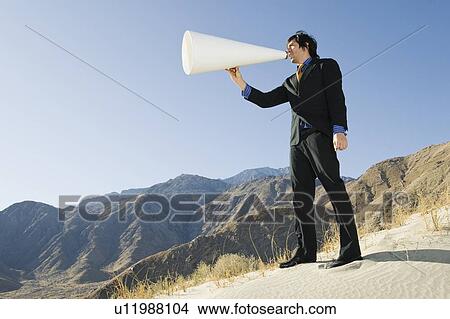 Picture - Businessman Using Megaphone in Desert. Fotosearch