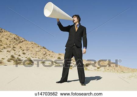 Stock Image - Businessman Using Megaphone in Desert. Fotosearch